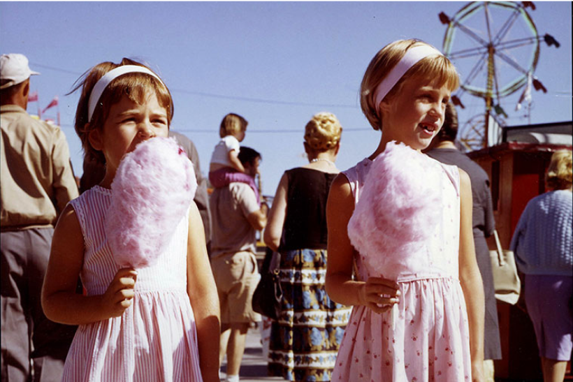 Image of two girls in pink dresses enjoying cotton candy.
